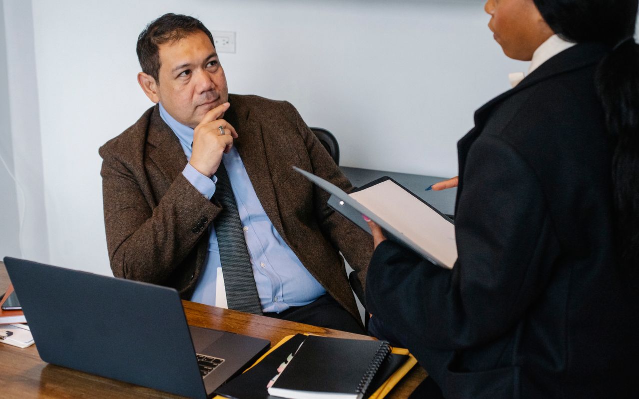 Gestor pratica escuta ativa durante conversa com colaboradora em ambiente corporativo. 